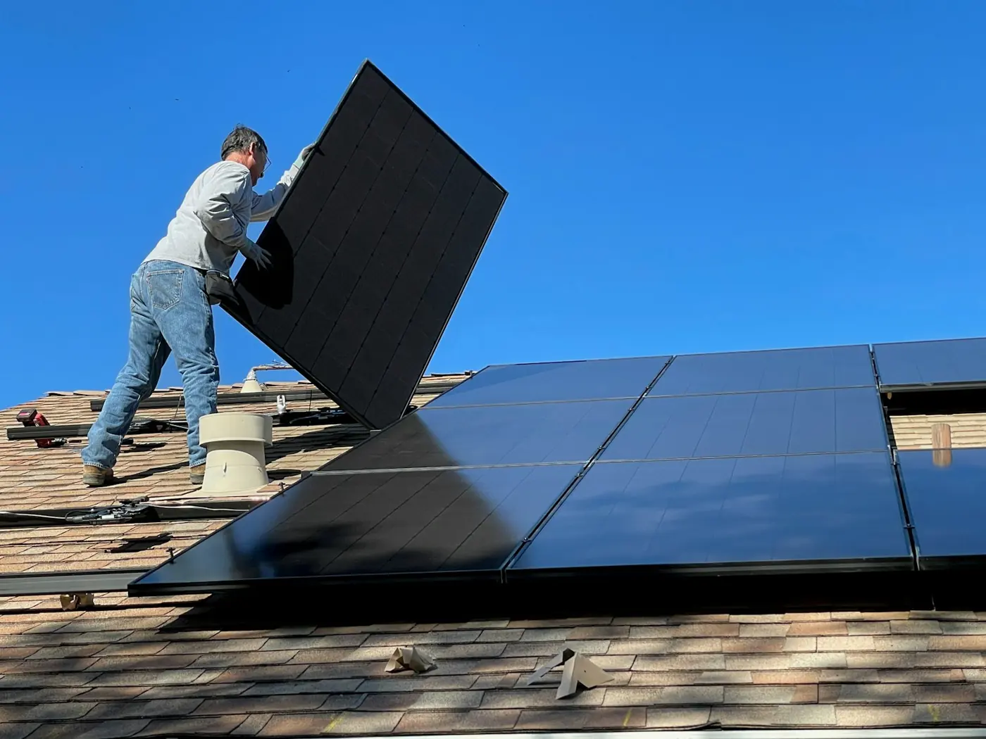 A worker fitting a solar panel onto a roof