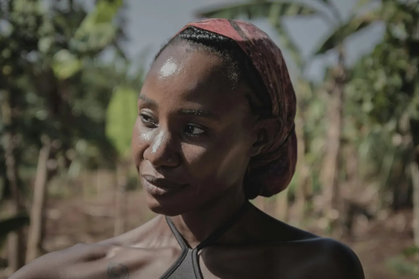 A woman in a headscarf standing among trees
